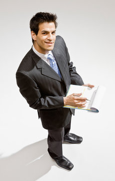Confident businessman writing on clipboard