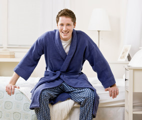 Man sitting on bed in bathrobe and pajamas
