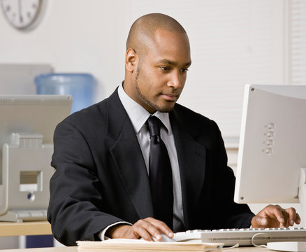 Serious businessman typing on computer at desk