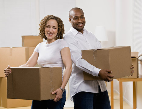 Couple moving into new home carrying cardboard boxes