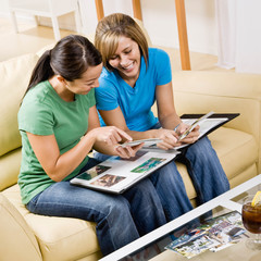 Friends sitting in livingroom looking at photograph album