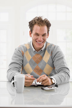 Happy young man working at desk at home, smiling.