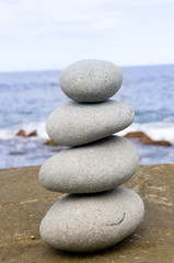 Fototapeta na wymiar Four stones balanced on a large rocky beach.