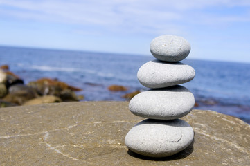 Four stones balanced on a large rocky beach