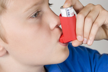 Asthma inhaler being used by boy in blue shirt