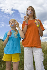 Children blowing bubbles on summer meadow