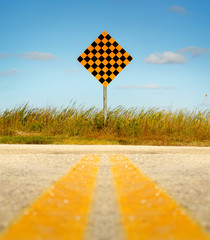 Paved road leading to dead end sign against a blue sky.