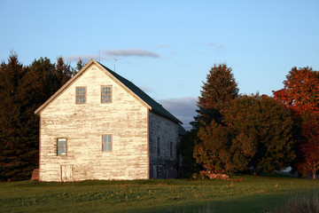 Fototapeta na wymiar Old White Barn under Blue Sky in rural Maine
