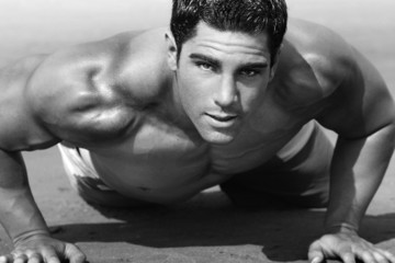 young man with naked torso doing push-ups on the beach - 9764308