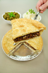 Slice of beef pie with peas and mashed potato ready to serve.