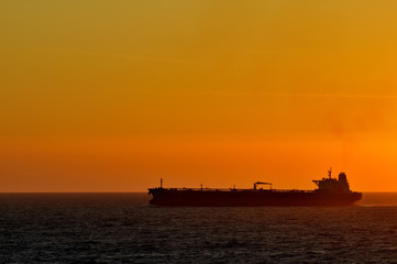 Obraz premium cargo ship by sunset at the ocean