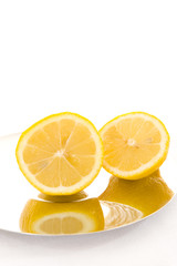 Fresh slices of lemon on shiny plate with white background.