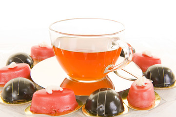 Red tea in a glass cup with some colorful confectionery.