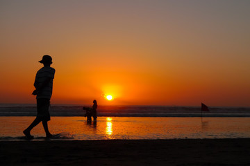 A young man walking on the beach at sunset, Kuta Beach, Bali