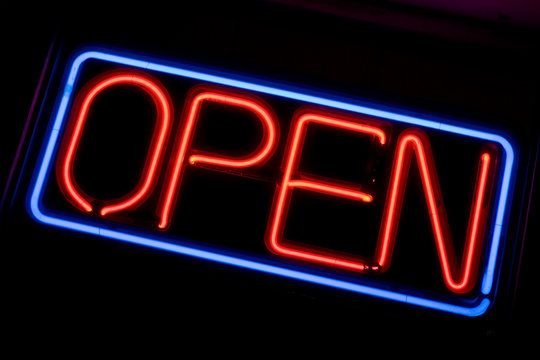A neon OPEN sign glowing red in the window of a restaurant