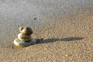 Fototapeta na wymiar Balanced stones on sand at seashore