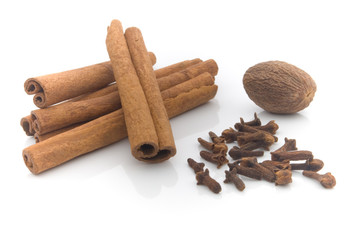 nutmeg, cinnamon and cloves on white background