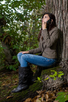 young woman talking by phone on deep forest
