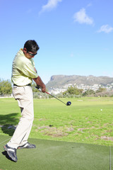 Attractive young golfer in action on a golf driving range.