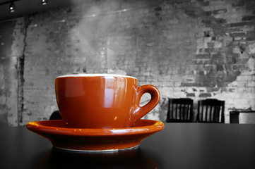 Cappuccino coffee cup and saucer in a brick cafe interior