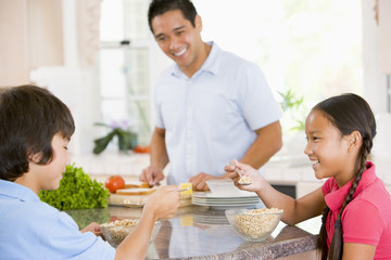 Children Having Breakfast While Dad Prepares Food