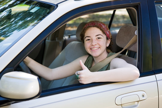 Cute teen driver giving the thumbs up after her driving test.