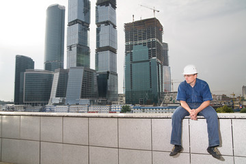 Pensive architect sitting in front of a building site