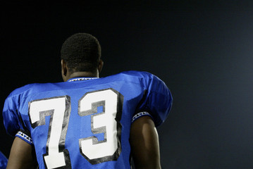 Football player at the side line watching the game.