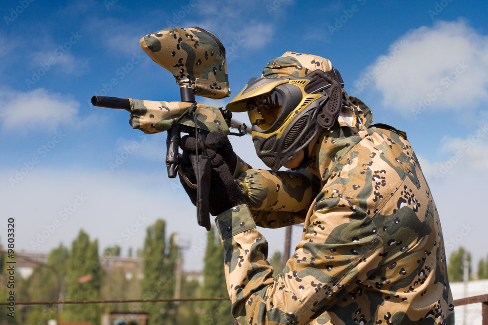 Wall mural portrait of a paintball player over blue sky background