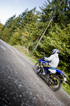 Motion blurred motocross rider, driving fastr through forest