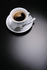 Close up of a white cup of coffee on black background