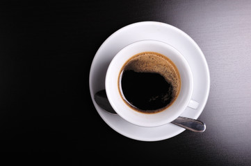 Obraz na płótnie Canvas Top view of a white cup of coffee on black background