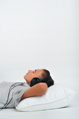 Young boy relaxing on pillow with headphones on ears