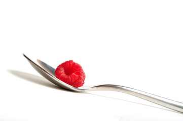 Close up of red raspberry on a spoon, white background