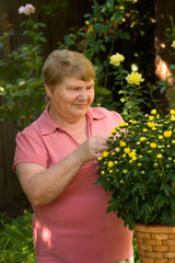 Happy elderly lady enjoys her time in a garden..