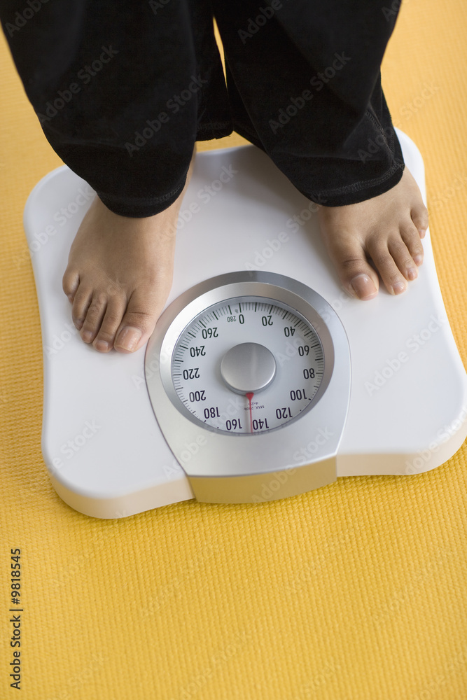 Wall mural black woman weighing herself on a bathroom scale