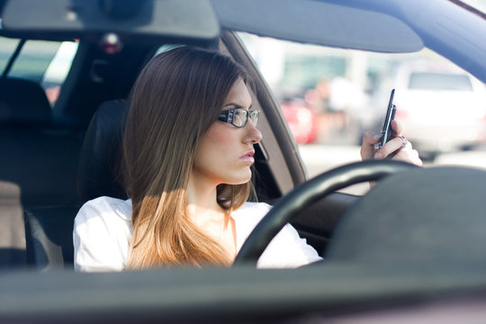 Confident woman dialing phone number while sitting in car