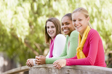 Teenage Girls Leaning On Wooden Railing