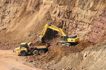 A Backhoe and dumptruck at rock quarry