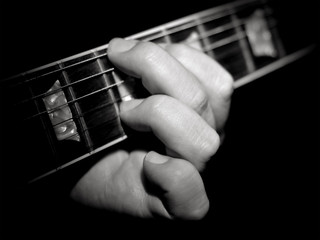 Guitar player fretboard playing chords on black background
