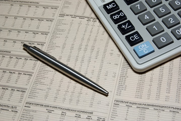 Professional calculator, steel pen and financial newspaper.