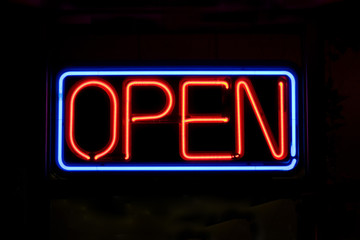 A neon OPEN sign glowing red in the window of a restaurant. - obrazy, fototapety, plakaty