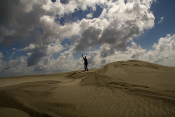 Fototapeta na wymiar A lonely man standing on a sand dune
