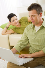 Couple browsing internet on laptop computer at home.