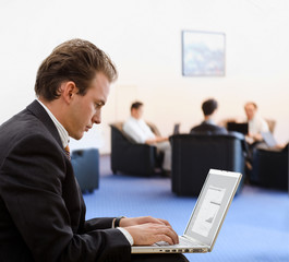 Businessman working on laptop computer at office lobby.