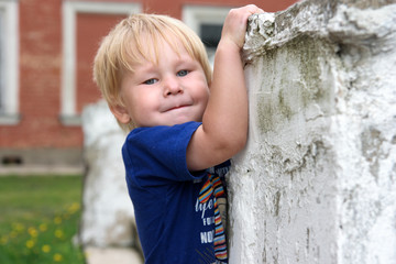 One active child plays about a white wall and smiles