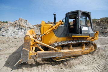A bulldozer works in an open-pit granite quarry.