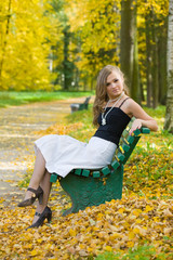 The beautiful girl on a bench in autumn park