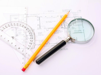 Small magnifier, protractor and pencil on the flat plan