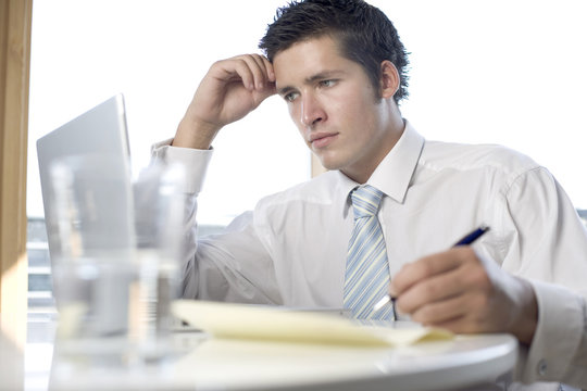 business man at his desk with a glass of water, wrighting